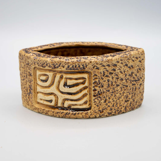 Ceramic pot with textured surface and geometric design on a white background