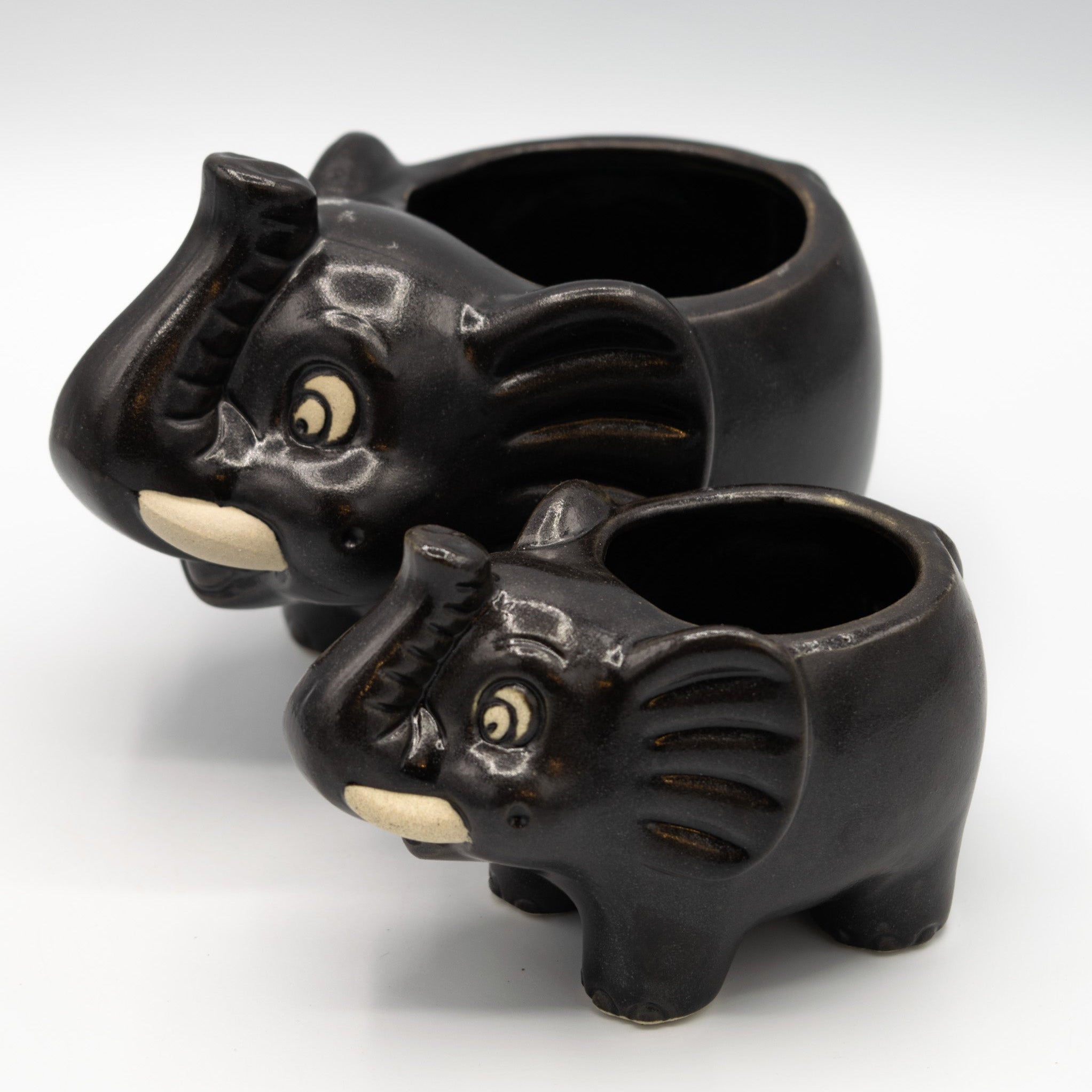 Two black elephant-shaped ceramic pots on a white background