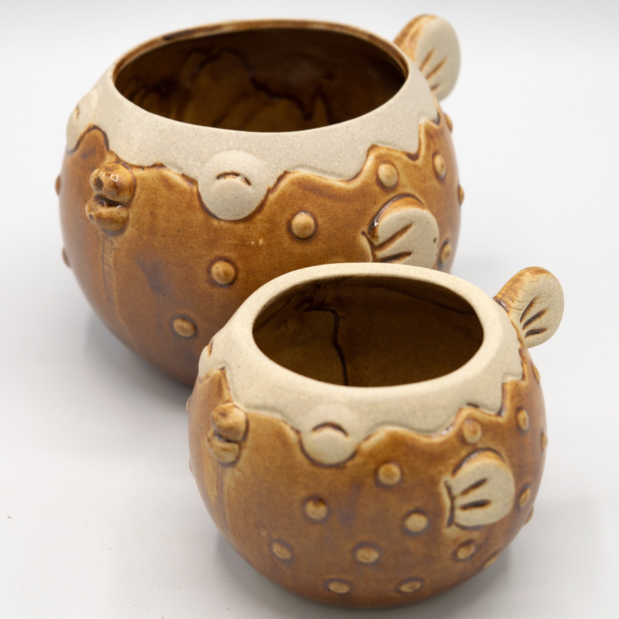 Two ceramic pots with fish design on a white background