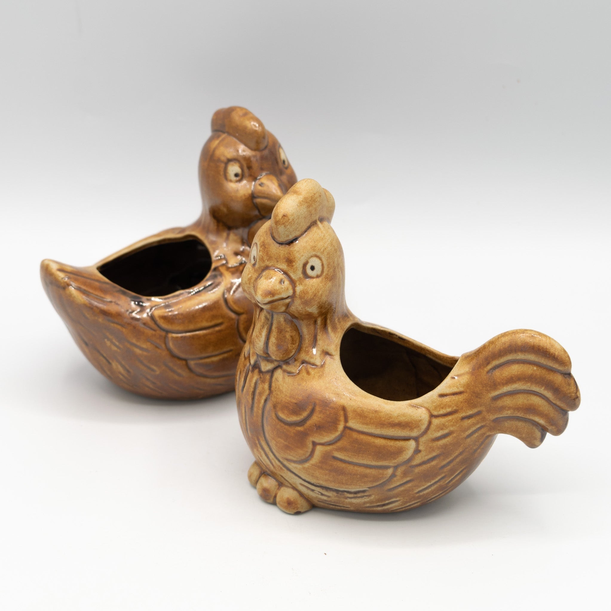 Two ceramic rooster-shaped containers on a white background