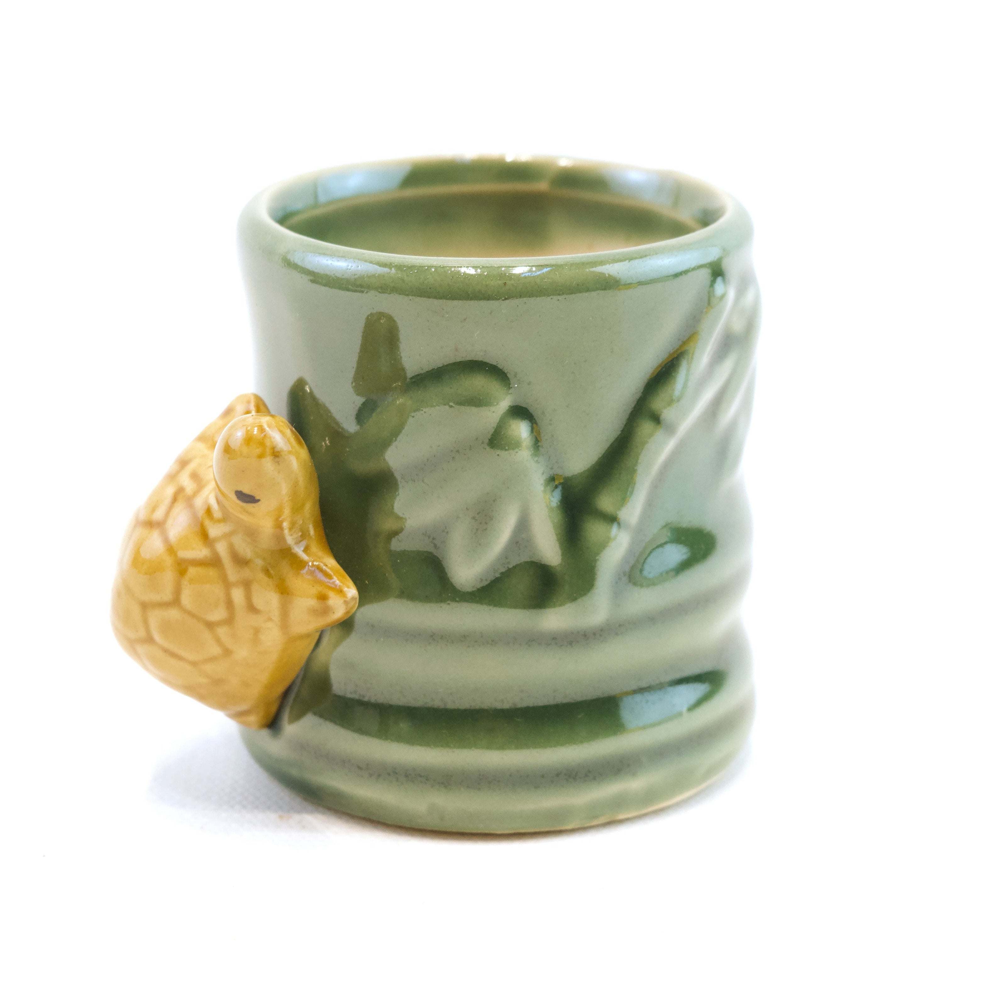 Green ceramic mug with a turtle design on a white background